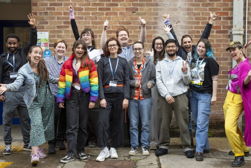 A group of students stood in front of a red brick wall 